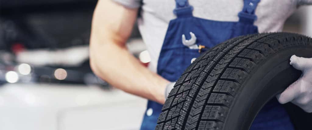 dealership mechanic holding tire